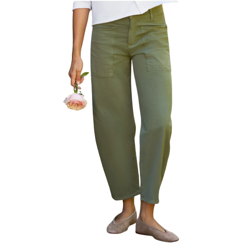 Person wearing green pants holding a small pink flower on a white background
