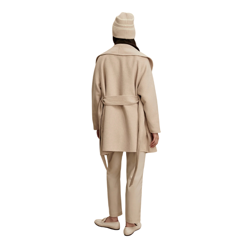Person wearing a beige coat and pants set on a white background