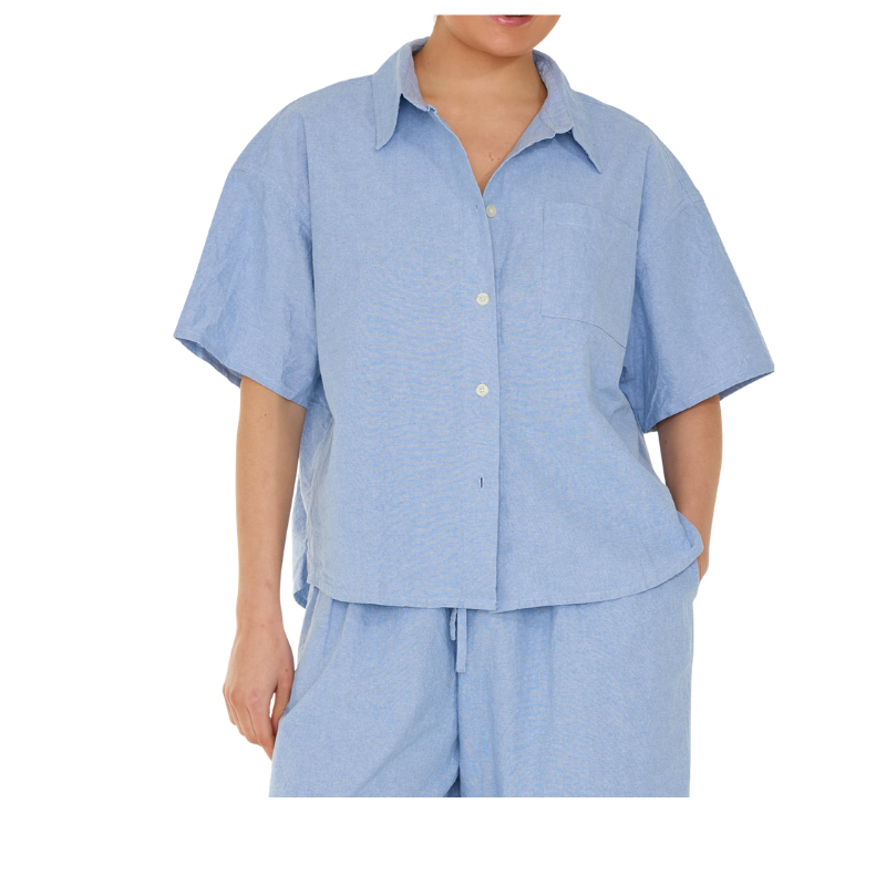 Person wearing a light blue shirt and pants set on a white background