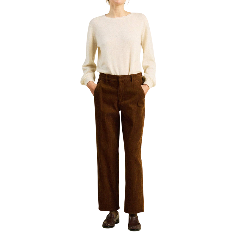 Person wearing a cream sweater and brown pants on a white background