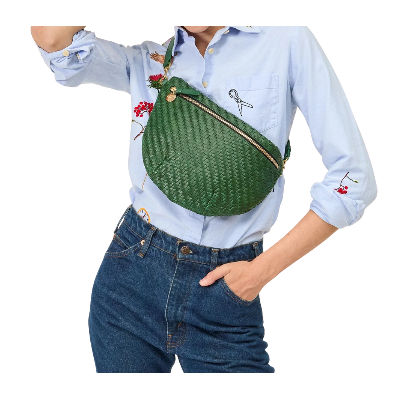 Person wearing a green woven waist bag with a white background