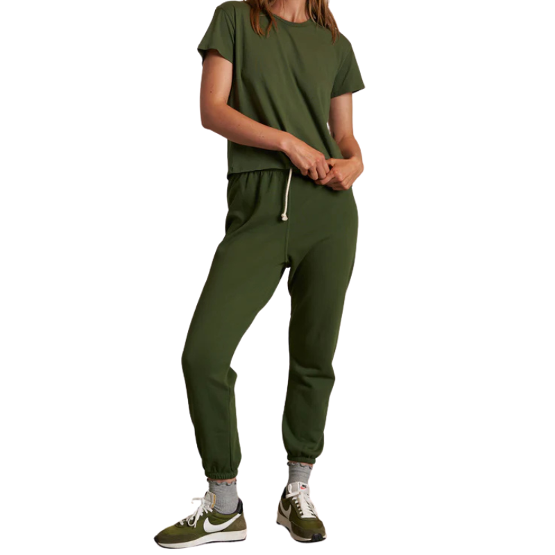 Person wearing a green tracksuit with Nike shoes on a white background