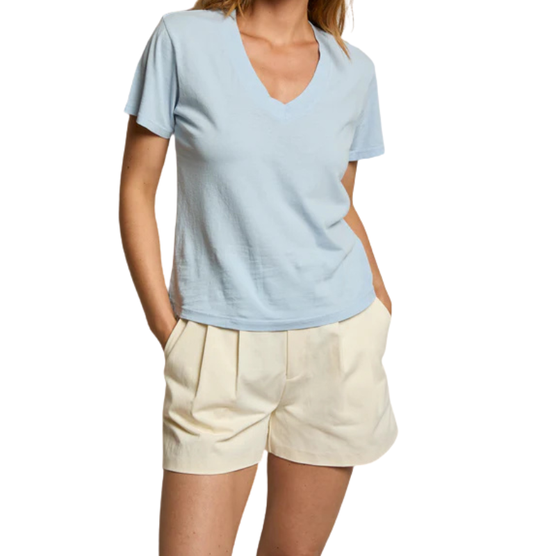 Person wearing a light blue shirt and beige shorts on a white background