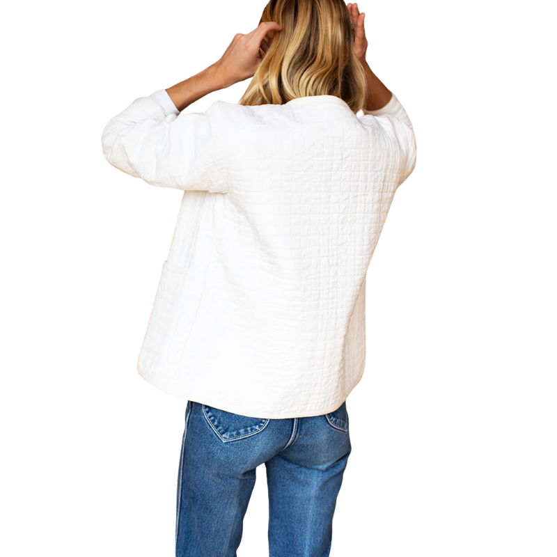 Person wearing a white textured sweater and blue jeans on a white background