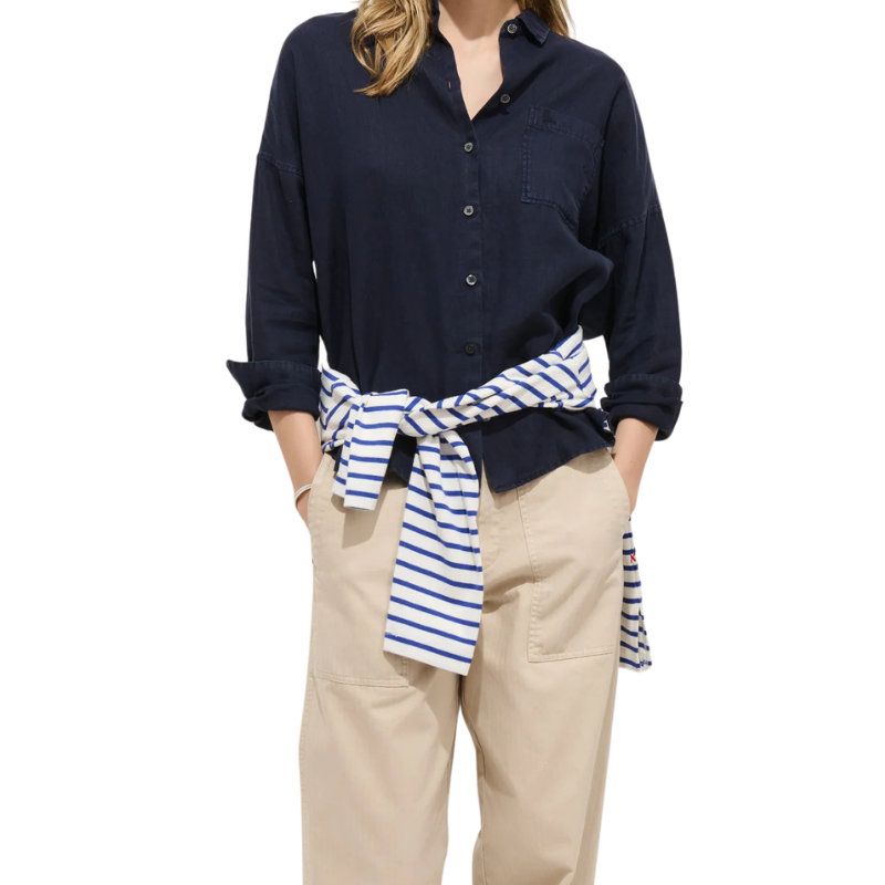 Person wearing a navy shirt with a striped tie and beige pants on a white background