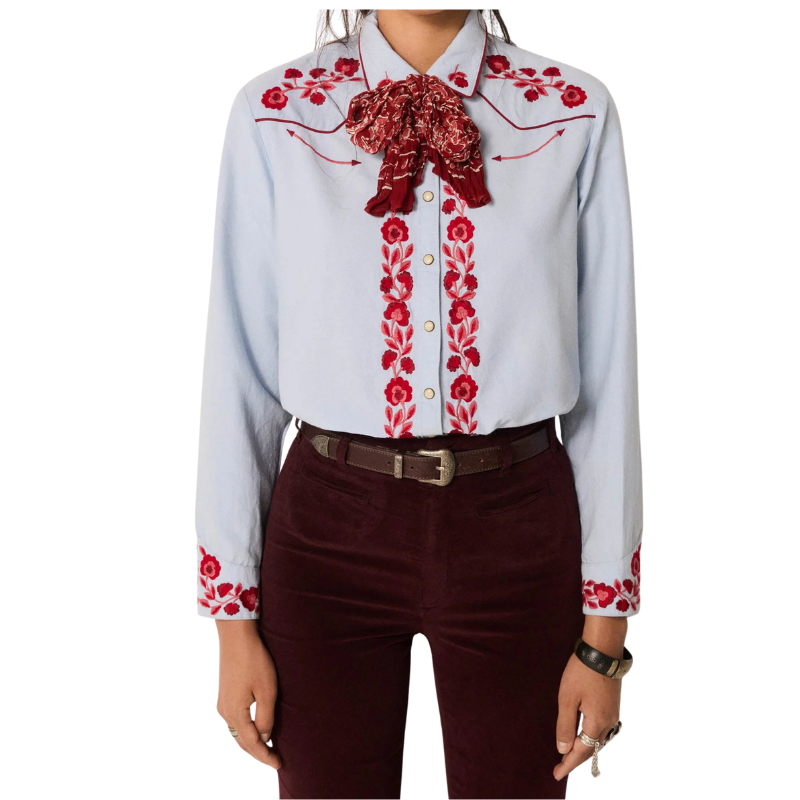 Light blue shirt with red floral embroidery and a red scarf, paired with dark pants on a white background.