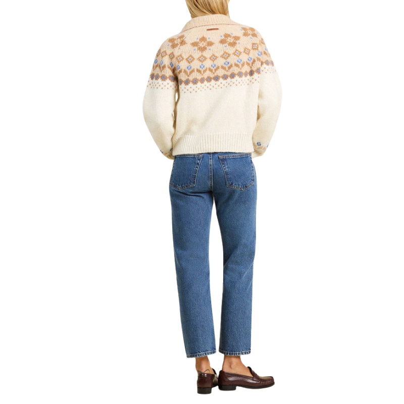 Person wearing a patterned sweater and blue jeans on a white background