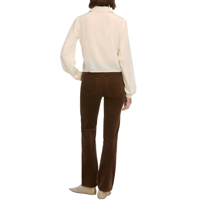 Person wearing a cream blouse and brown pants on a white background