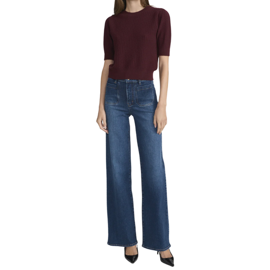 Person wearing a burgundy top and blue jeans on a white background