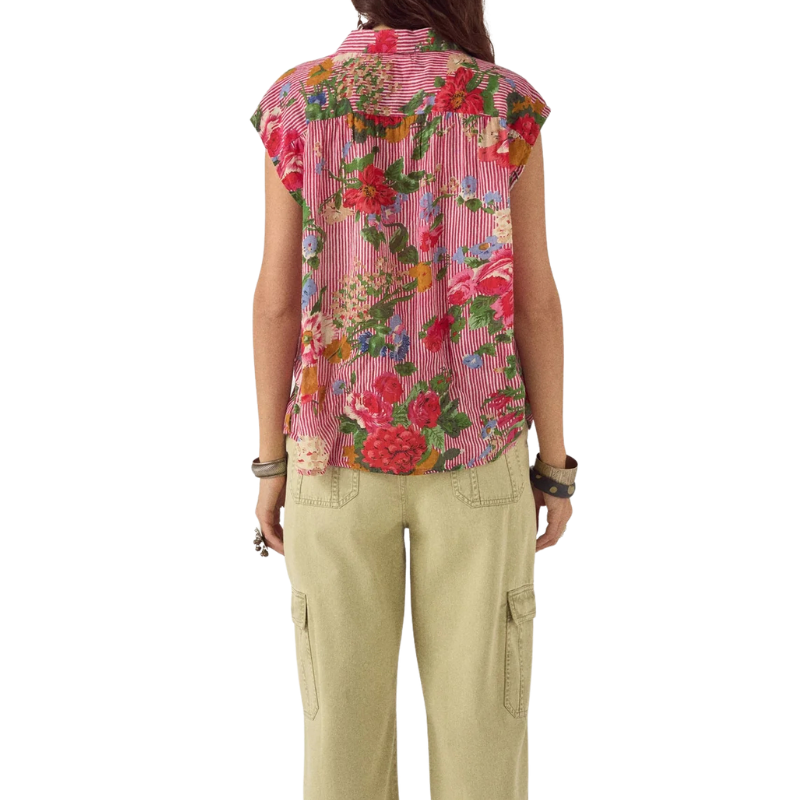 Person wearing a sleeveless floral blouse and beige pants on a white background