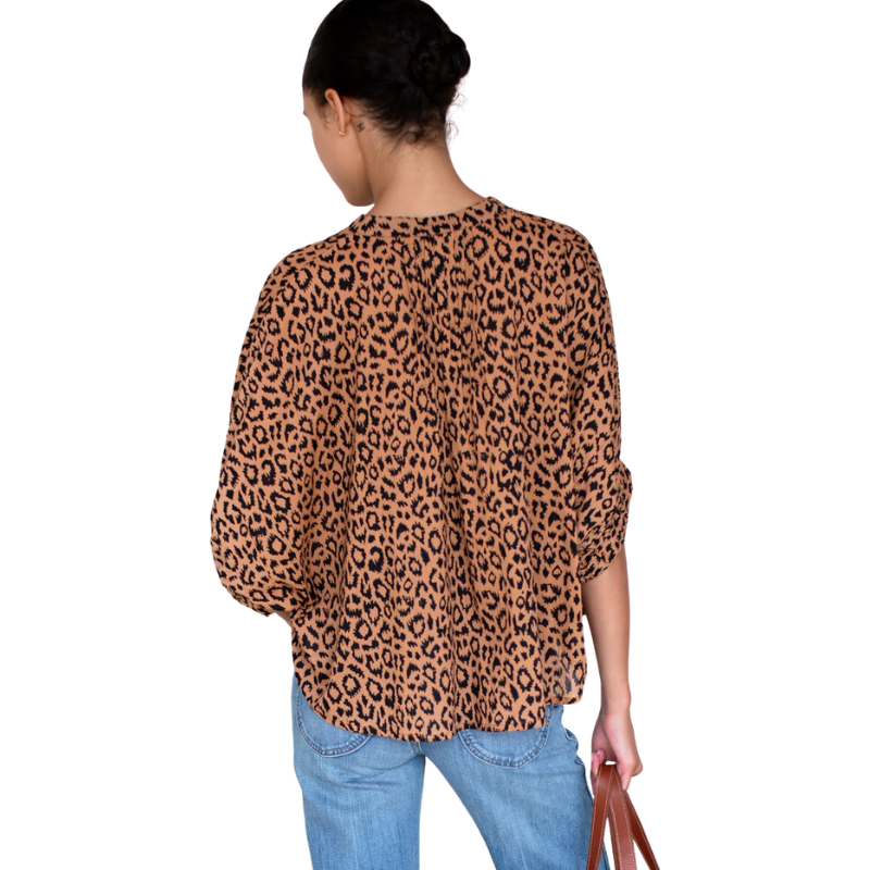 Person wearing a leopard print blouse and blue jeans on a white background