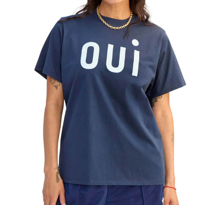 Person wearing a navy blue t-shirt with 'oui' printed on it against a white background