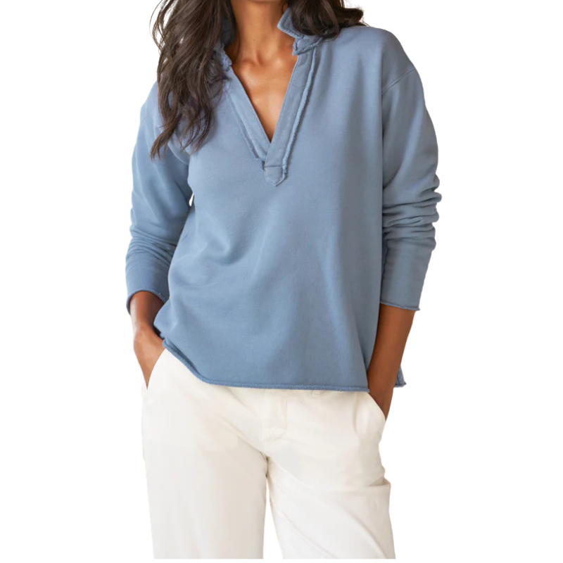 Woman wearing a light blue long-sleeve top and white pants on a white background
