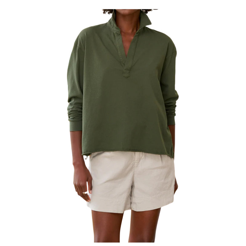 Person wearing a green long-sleeve shirt and beige shorts on a white background