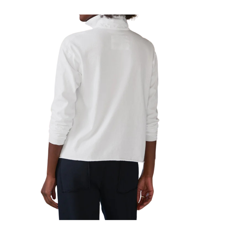Person wearing a white turtleneck sweater and dark pants on a white background