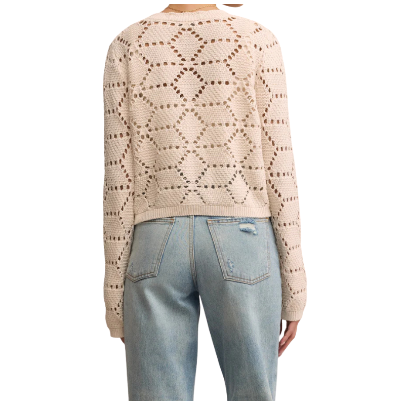 Beige patterned sweater and light blue jeans on a white background