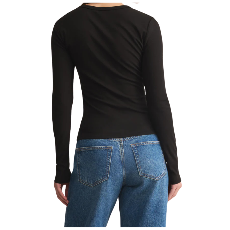 Person wearing a black long-sleeve top and blue jeans on a white background
