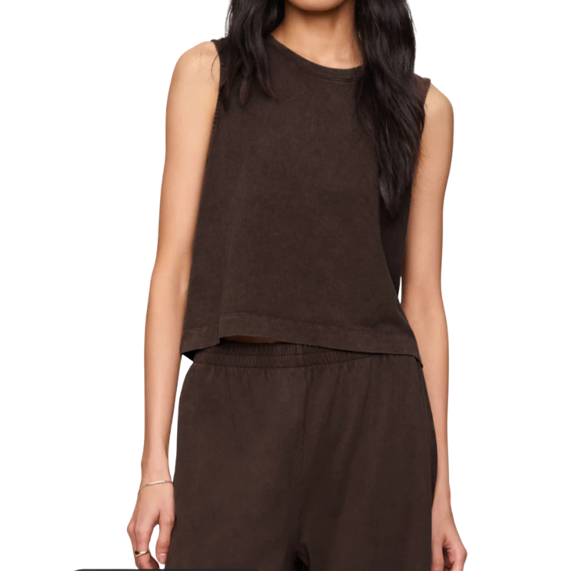 A woman wearing a dark brown sleeveless cropped top and matching dark brown pants against a plain white background.