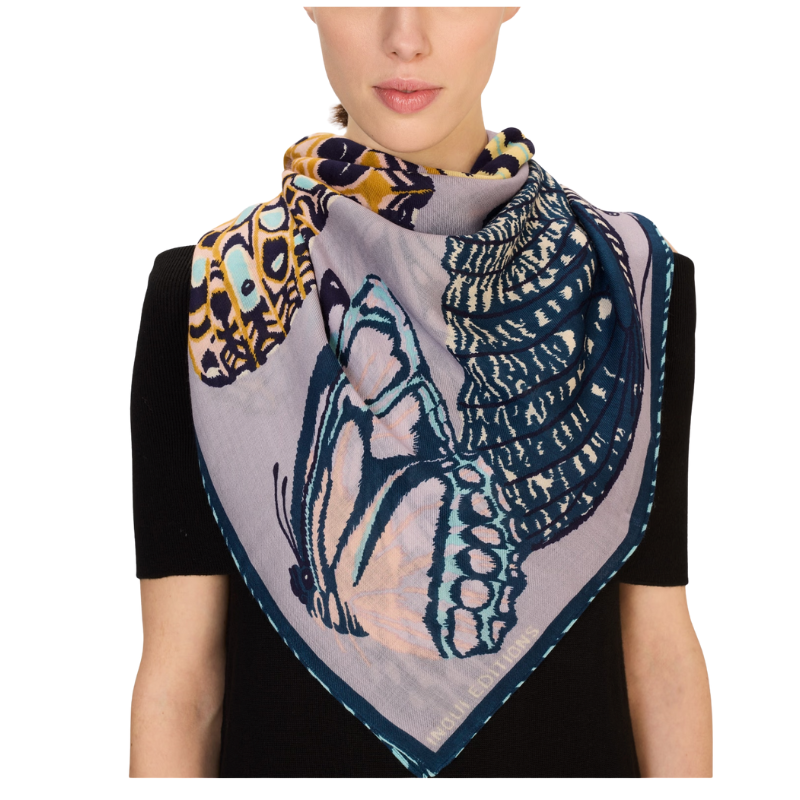 Person wearing a colorful butterfly patterned scarf on a white background