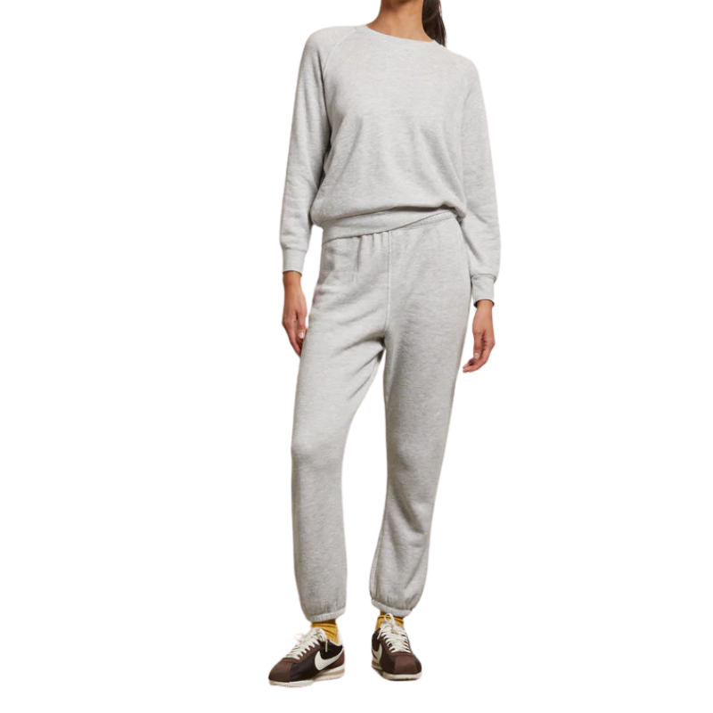 Person wearing a gray sweatshirt and pants set on a white background
