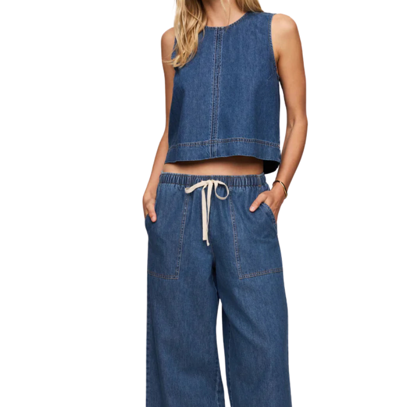 Woman wearing a denim sleeveless top and wide-leg pants on a white background