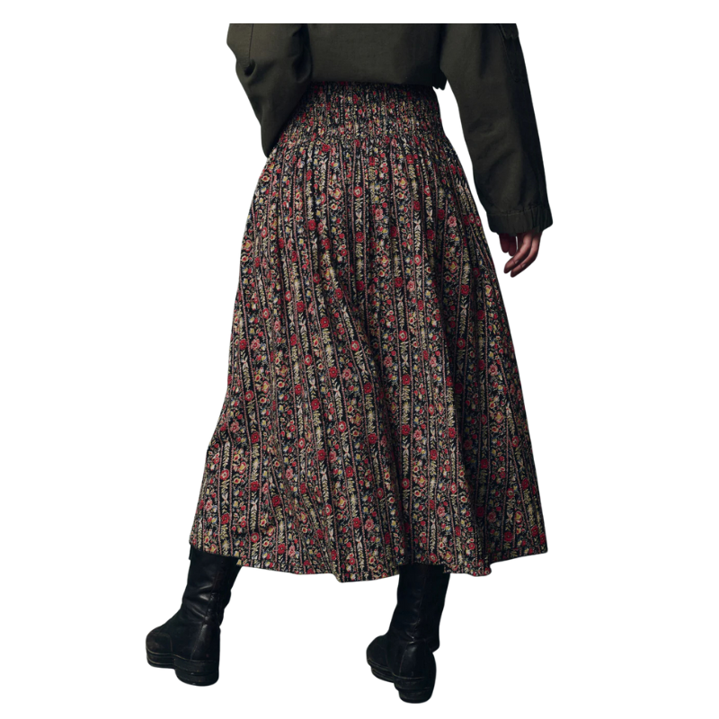 Person wearing a patterned skirt and black boots on a white background