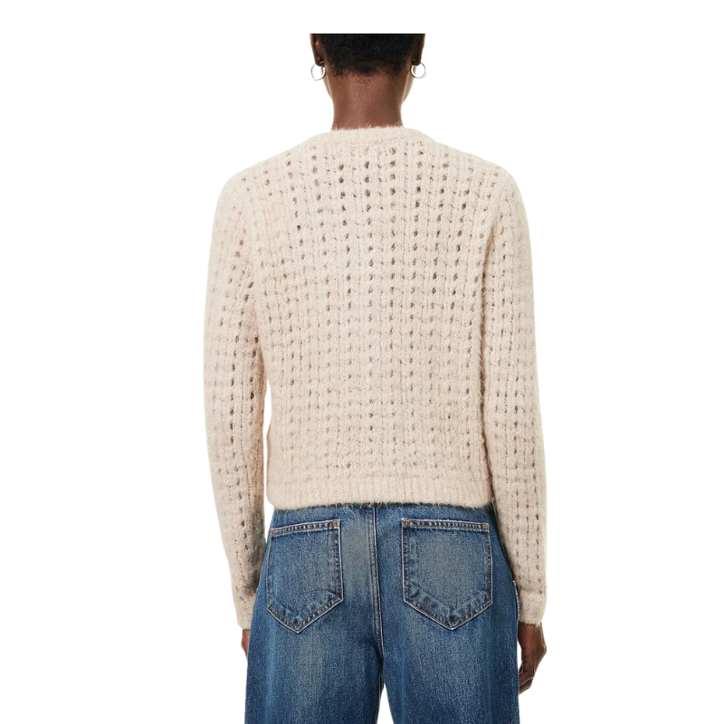 Person wearing a textured beige sweater and blue jeans on a white background