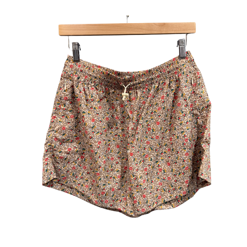 Floral patterned shorts on a wooden hanger against a white background