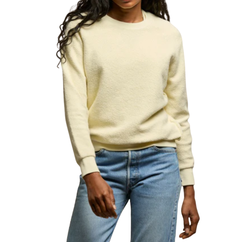 Person wearing a light yellow sweater and blue jeans on a white background