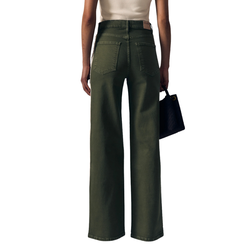 A model shown from the back wearing olive green wide-leg jeans, a cream top, and holding a black handbag against a plain white background.