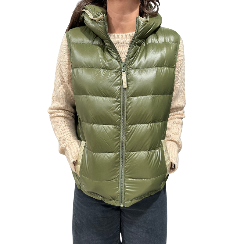 Person wearing a green puffer vest over a beige sweater on a white background