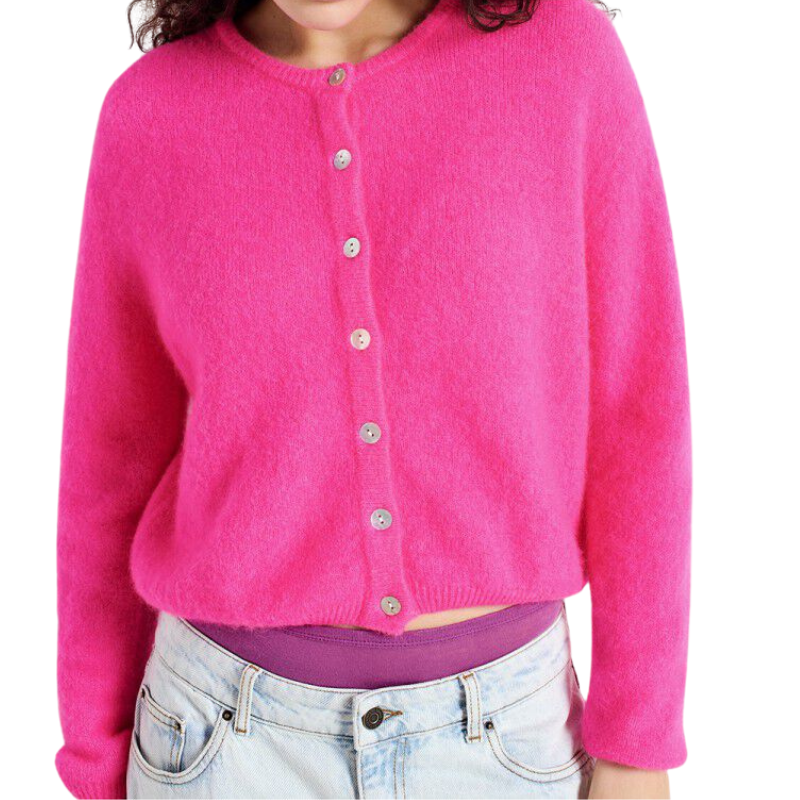 Person wearing a bright pink cardigan over a purple shirt with light blue jeans on a white background