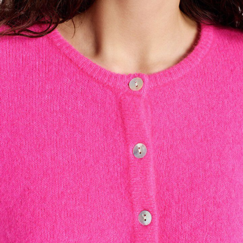 Close-up of a bright pink cardigan with buttons on a plain background