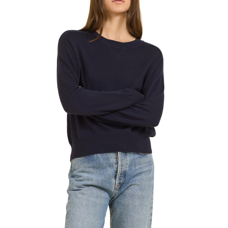 Person wearing a navy sweater and light blue jeans on a white background