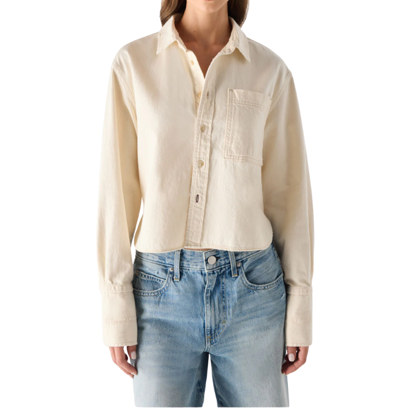 Person wearing a beige button-up shirt and blue jeans on a white background