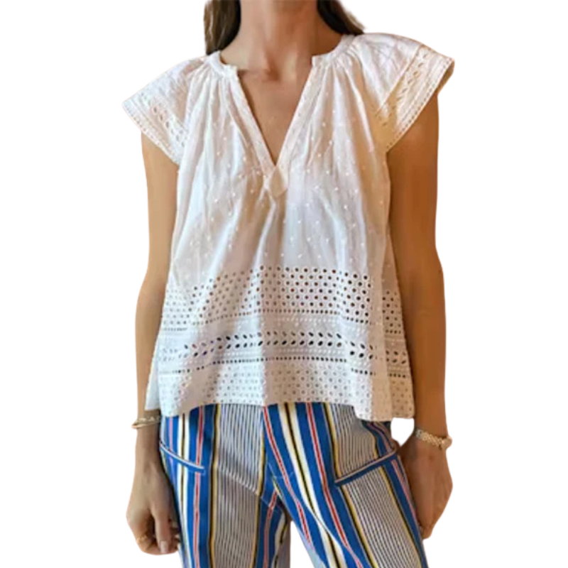 Woman wearing a white lace top and colorful pants on a white background