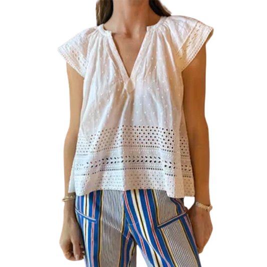 Woman wearing a white lace top and colorful pants on a white background