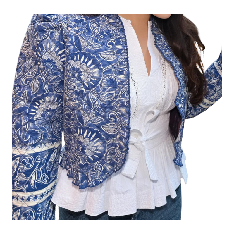 Blue patterned jacket over a white blouse on a person against a white background