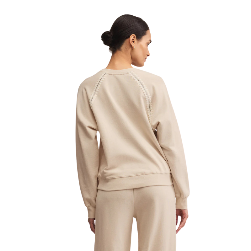 Woman wearing a beige sweatshirt and pants on a white background