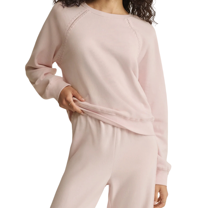 Light pink long-sleeve top worn by a person on a white background