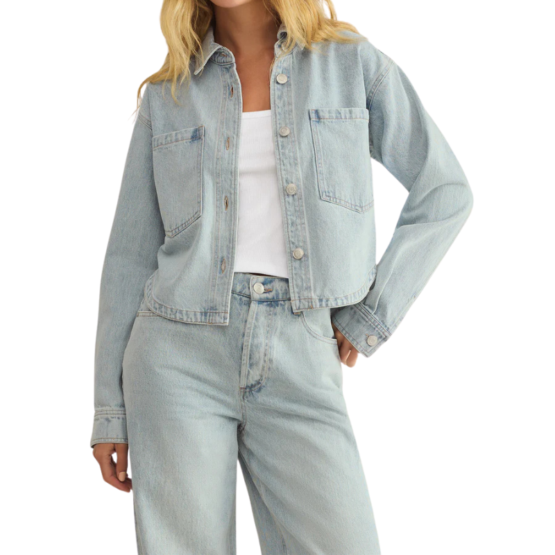 Person wearing a light blue denim jacket and jeans on a white background