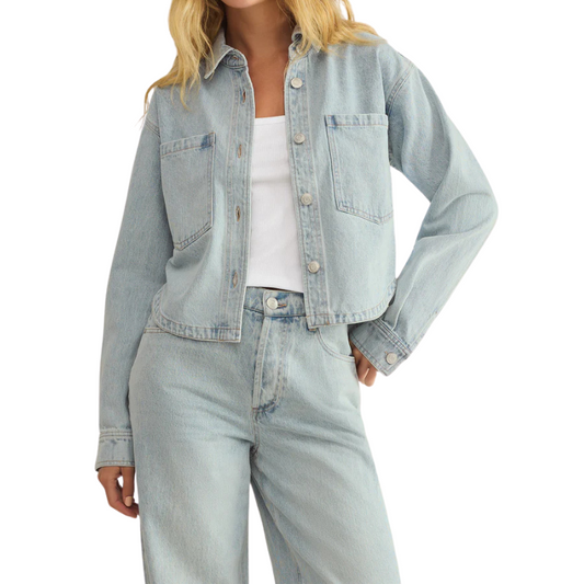 Person wearing a light blue denim jacket and jeans on a white background