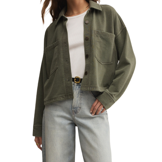 Person wearing a green jacket, white shirt, and light blue jeans on a white background