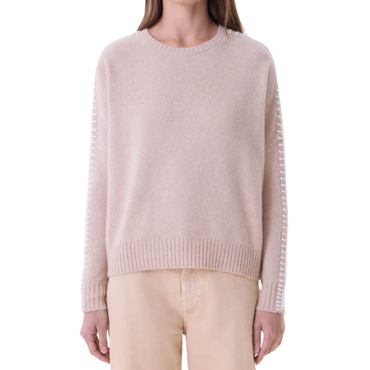 Person wearing a light pink sweater with ribbed sleeves on a white background