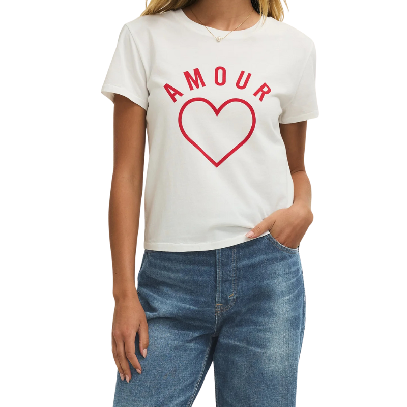 Person wearing a white t-shirt with 'AMOUR' and a red heart design, paired with blue jeans on a white background.