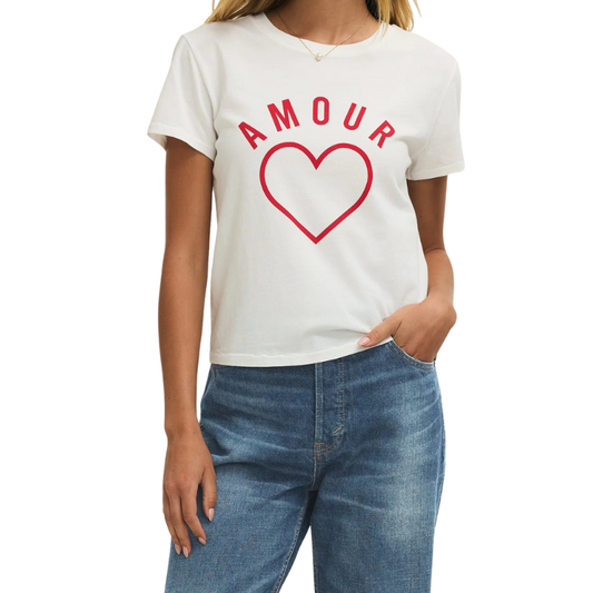 Person wearing a white t-shirt with 'AMOUR' and a red heart design, paired with blue jeans on a white background.
