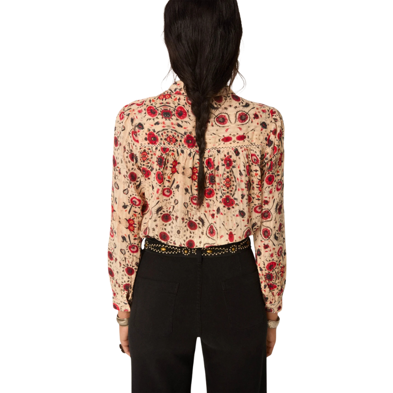 Person wearing a patterned blouse with long sleeves and a high collar on a white background