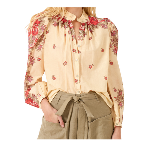 Beige blouse with floral sleeves and red flowers worn by a person on a white background