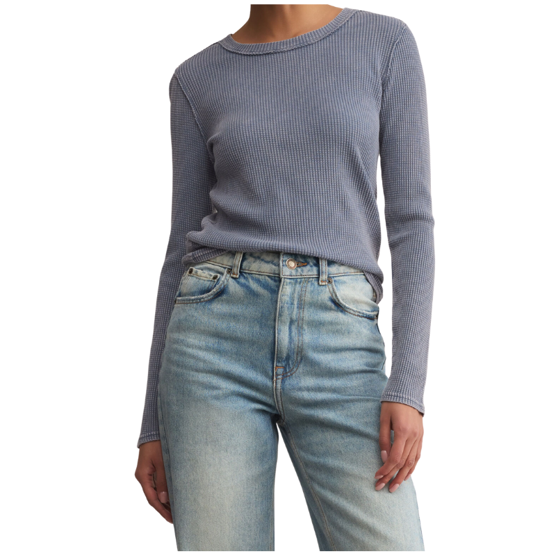 Person wearing a ribbed long-sleeve top and light blue jeans on a white background