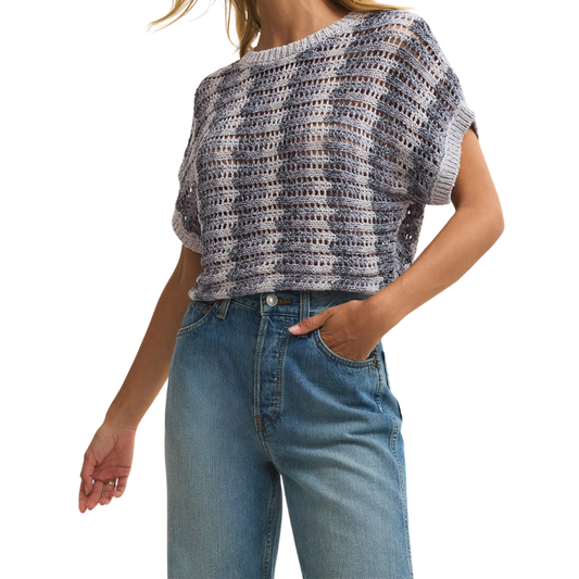 Person wearing a patterned top and blue jeans on a white background